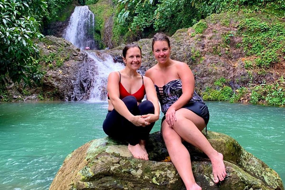 two women sitting on a rock in front of a waterfall