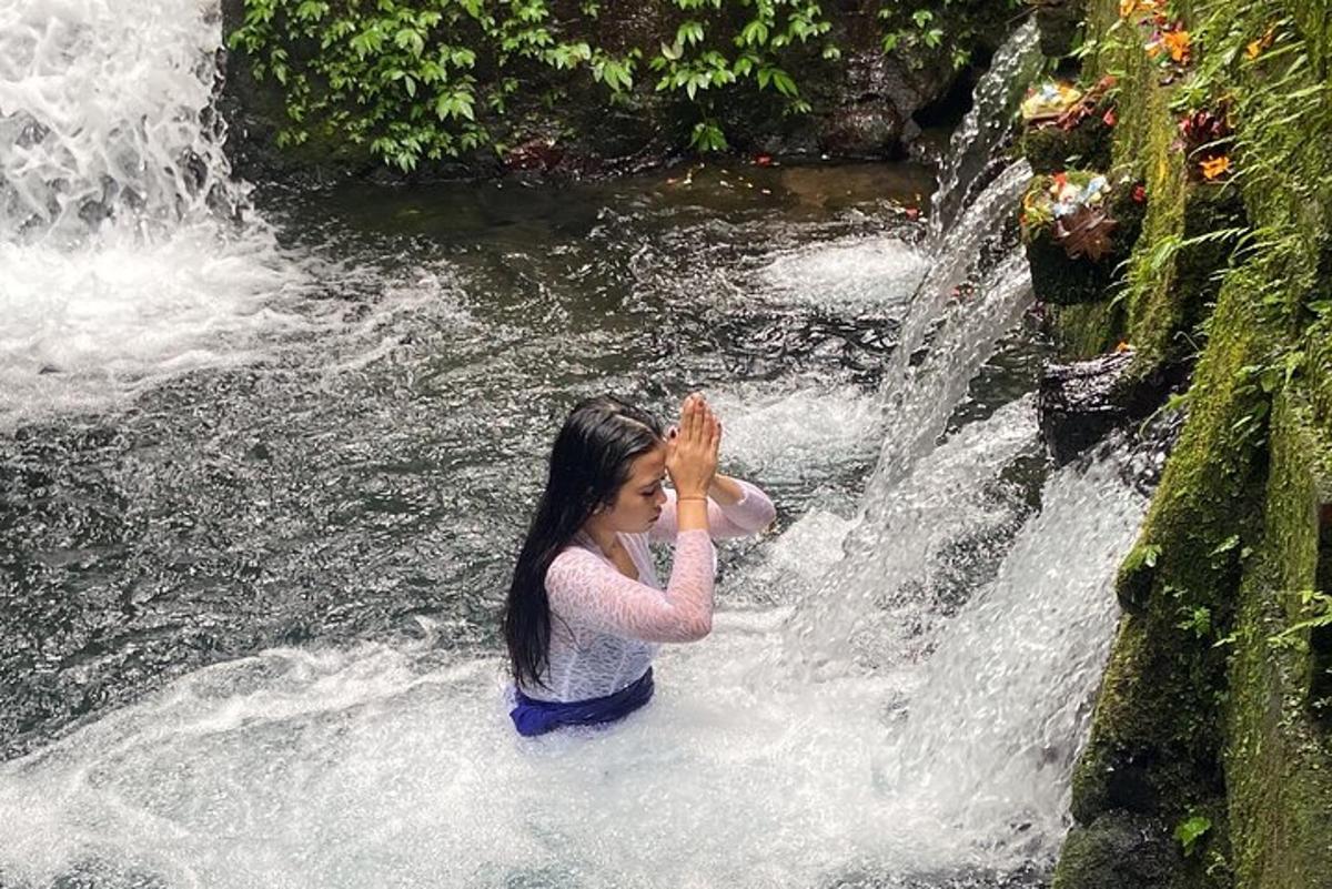 seorang wanita berdiri di depan air terjun