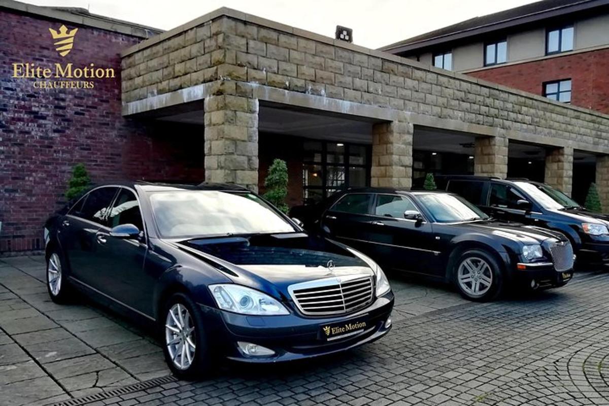 Dos coches estacionados en un estacionamiento frente a un edificio.