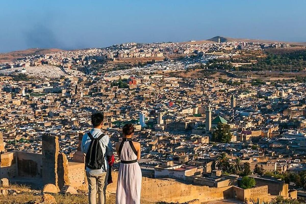 two people standing on top of a hill looking at a city