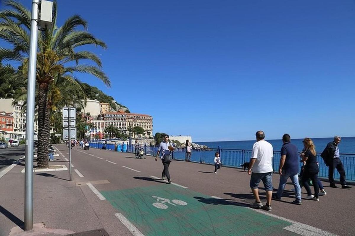 un grup de persones caminant per un carrer al costat de l'oceà