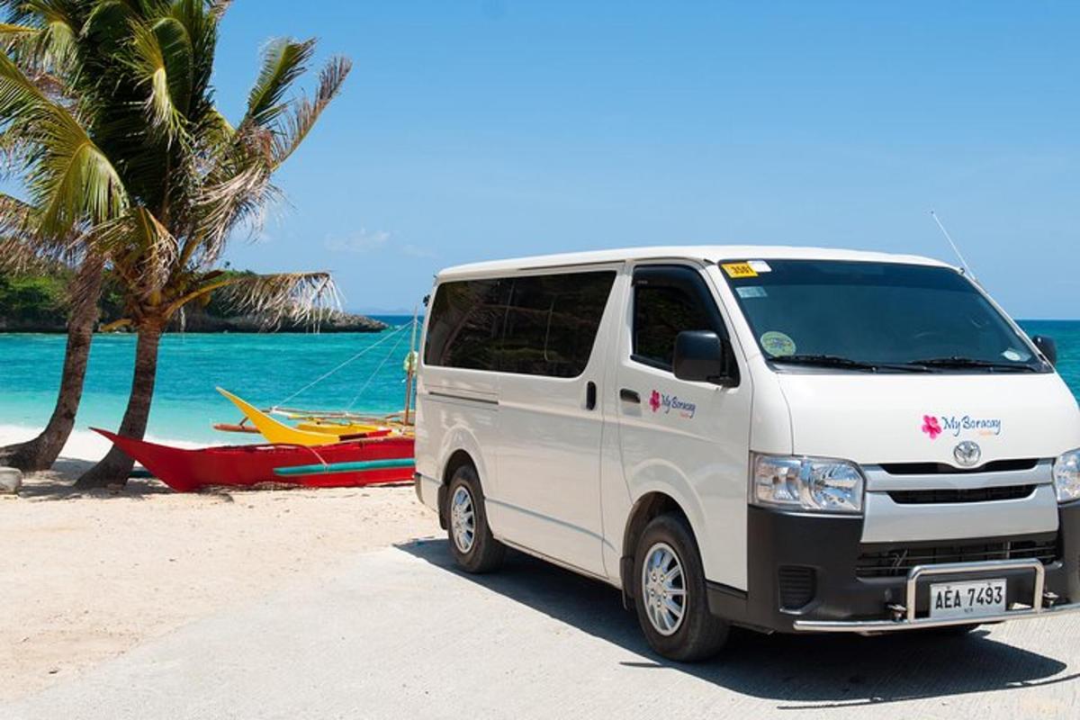 a white van parked on a beach next to a boat