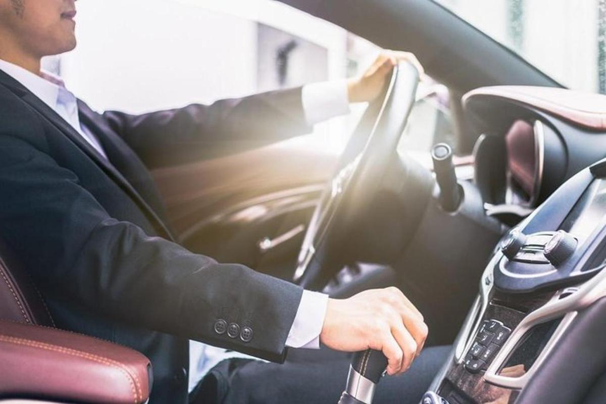 muž v obleku šoférujúci auto