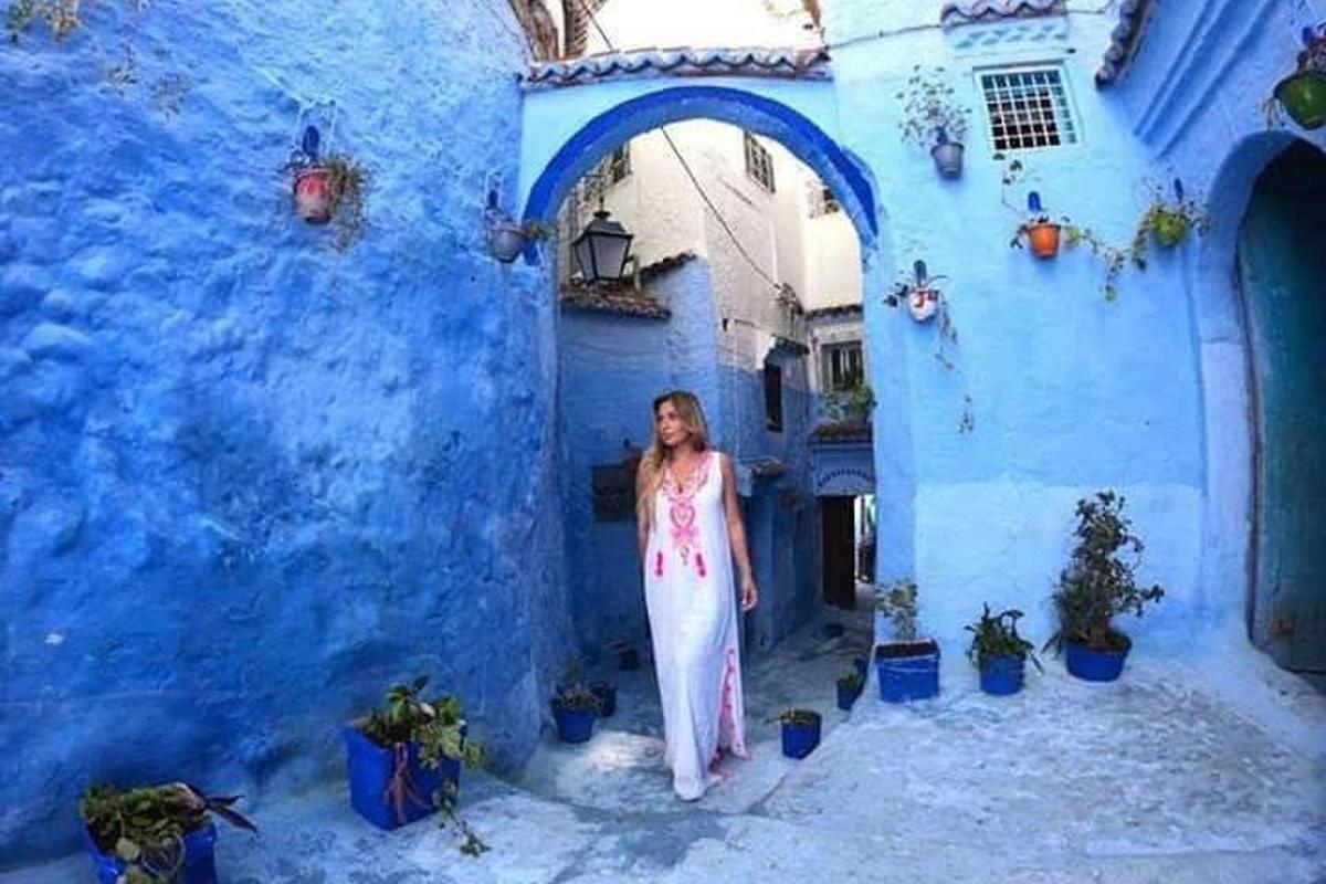 a woman standing in an alley in front of a blue building
