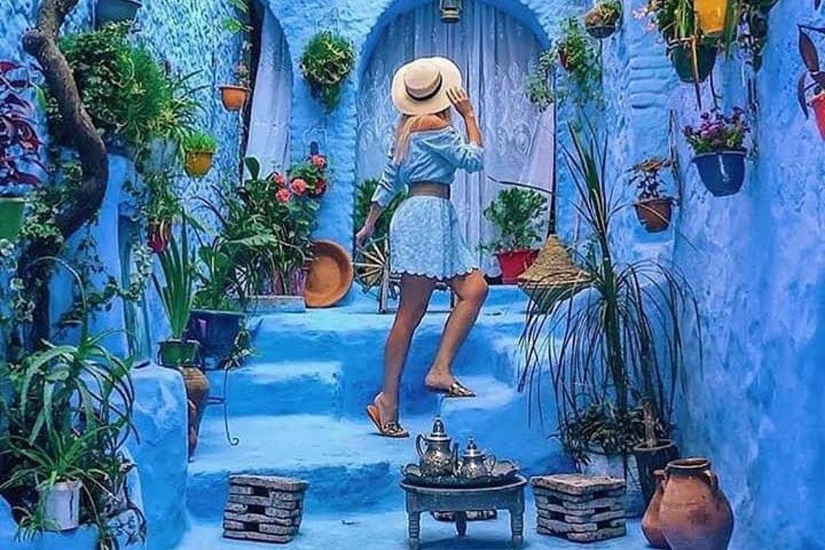un dipinto di una donna che indossa un cappello in piedi su un muro blu