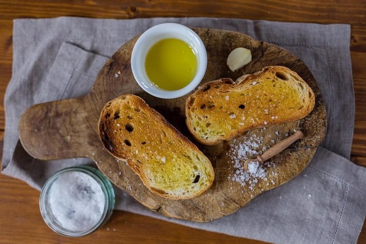 Dos rebanadas de pan en una tabla de cortar con una taza de miel.