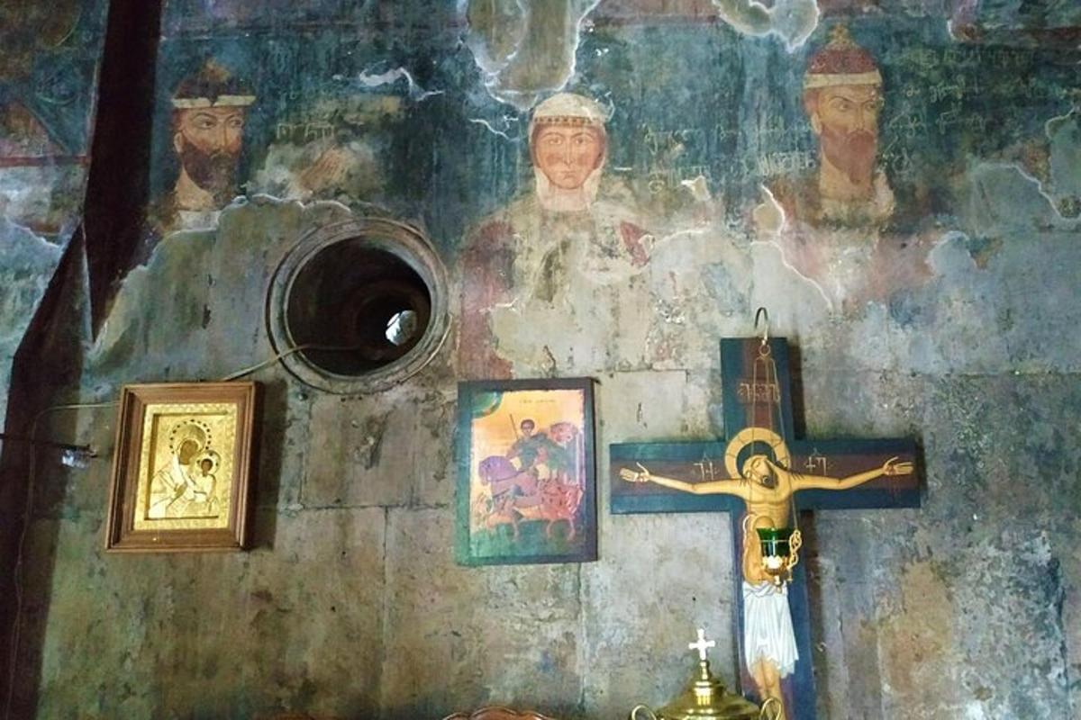 una croce su un muro con quadri e un dipinto
