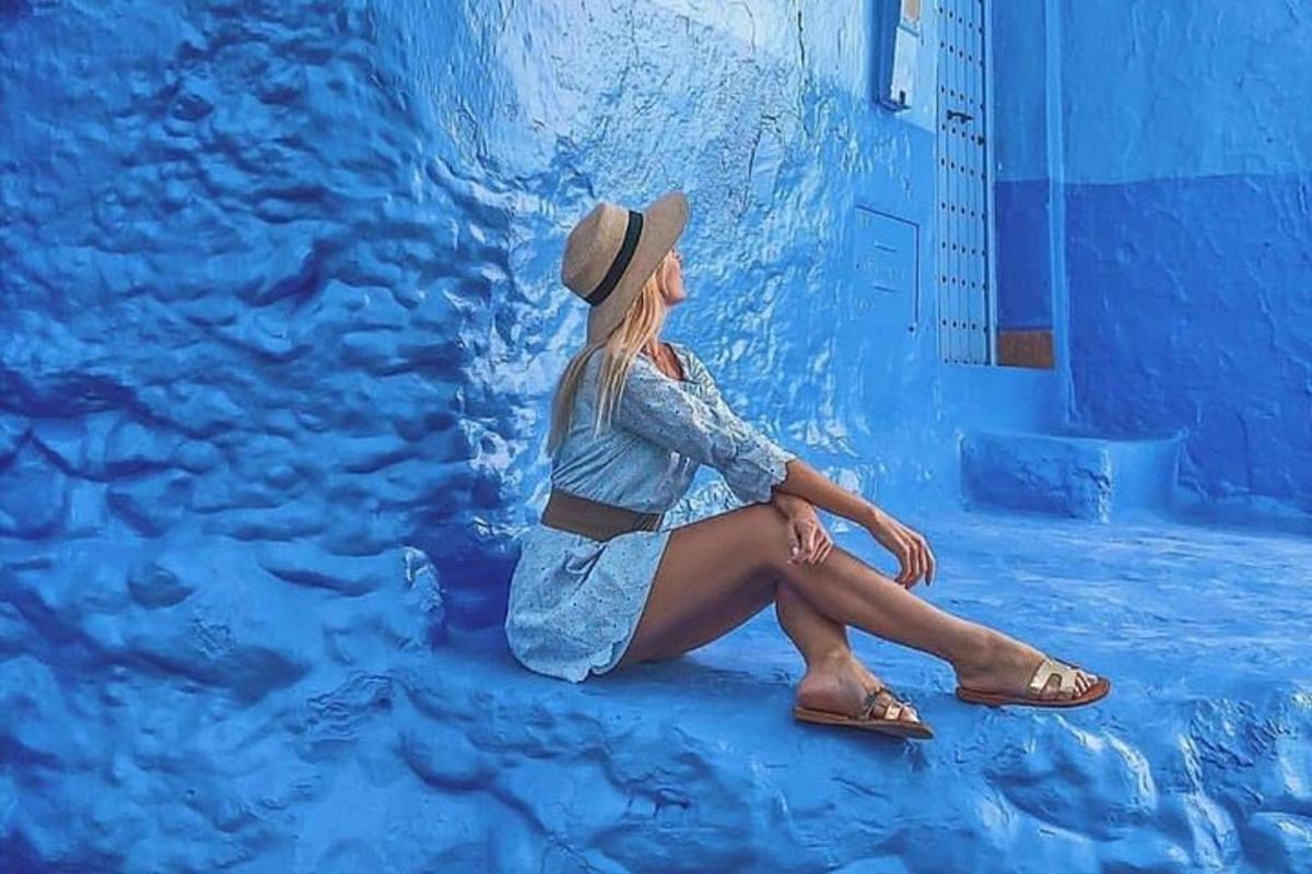 una donna con un cappello seduta su un muro