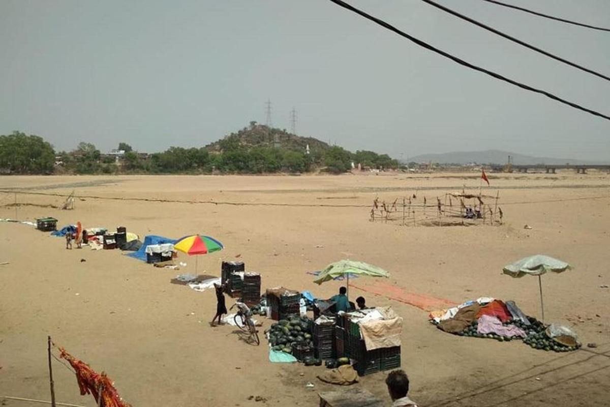 eine Gruppe von Menschen sitzt mit Sonnenschirmen an einem Strand