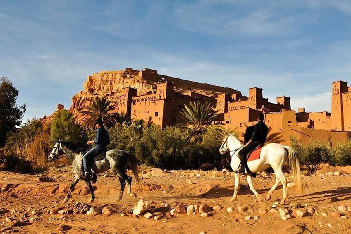 Dos personas montando a caballo frente a un castillo.