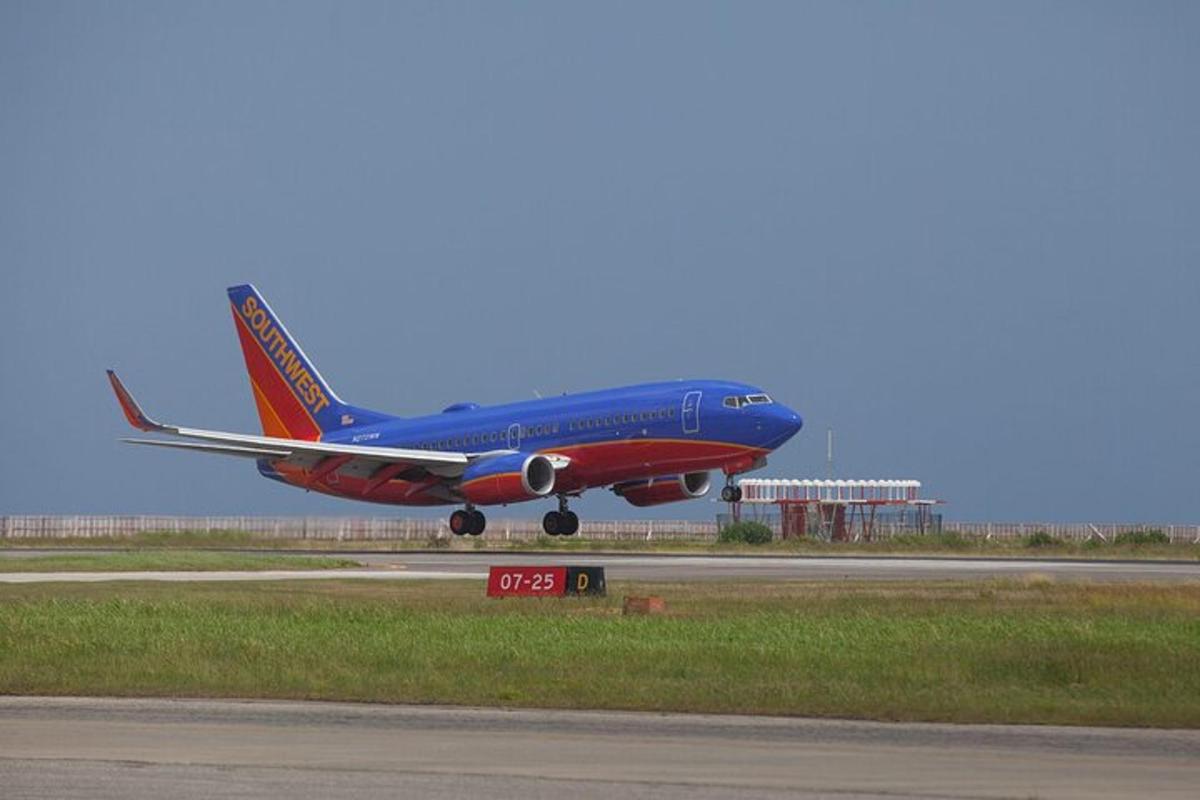 Un avión azul y rojo despegando de la pista de un aeropuerto.