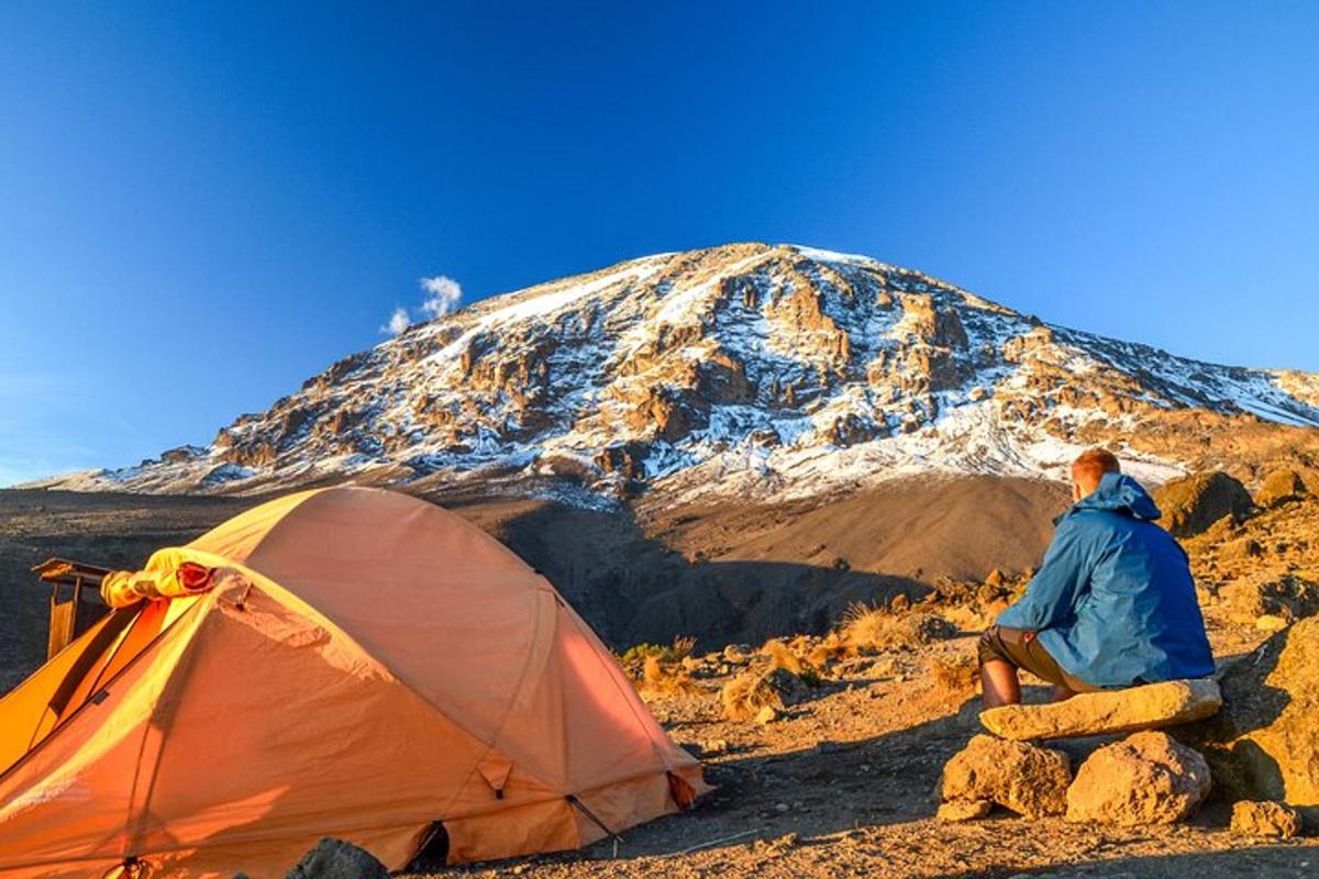 un uomo seduto accanto a una tenda e una montagna