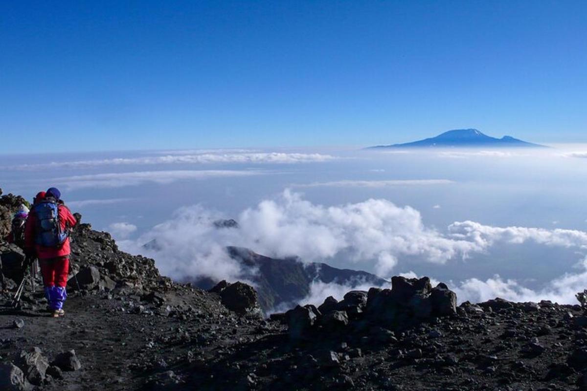 una persona parada en la cima de una montaña con nubes