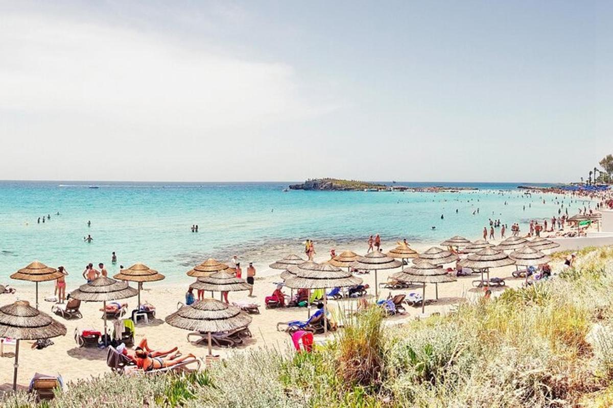 una platja amb molts para-sols i gent a l'aigua