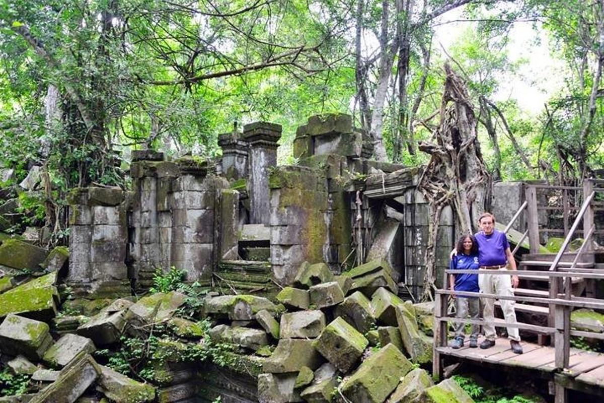 Un hombre y una mujer de pie en un puente frente a una estructura de piedra.