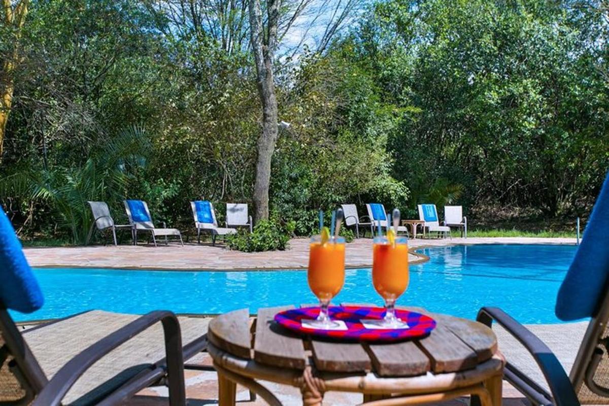 două pahare de suc de portocale pe o masă lângă piscină