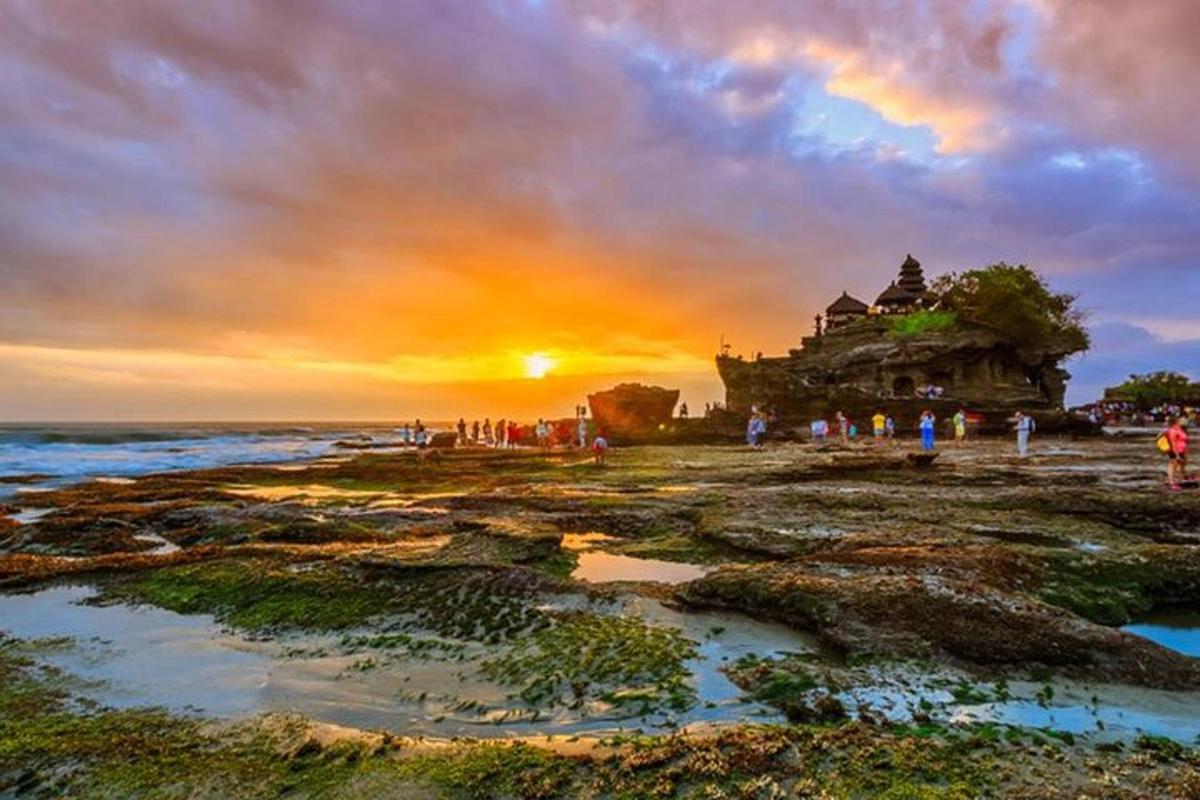 um grupo de pessoas em pé na praia com o pôr do sol
