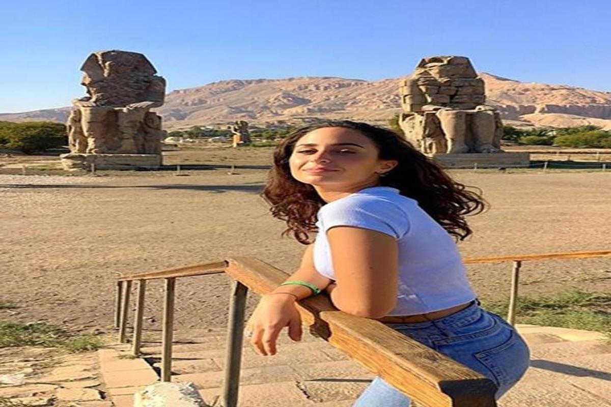 una mujer sentada en un banco frente a una estatua