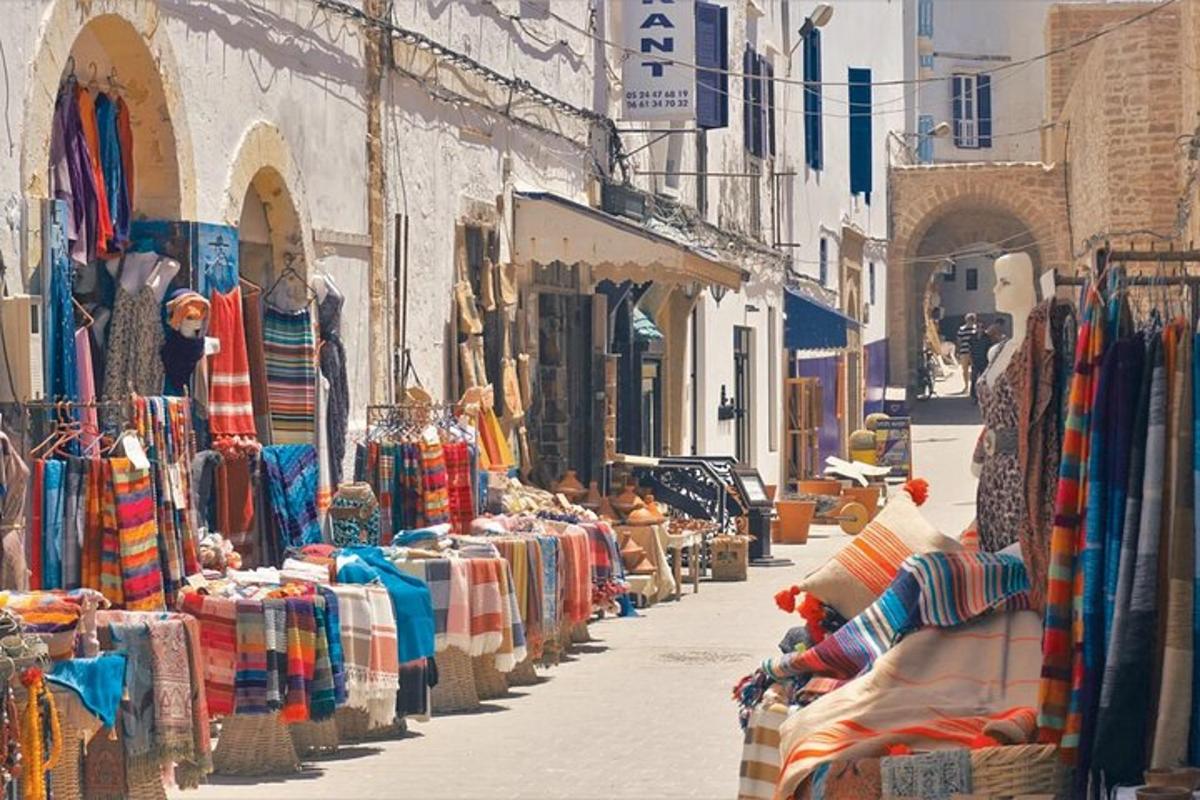 Una calle con una hilera de tiendas con ropa en exhibición.