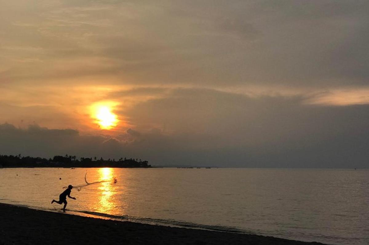 una persona jugando con una cometa en la playa al atardecer