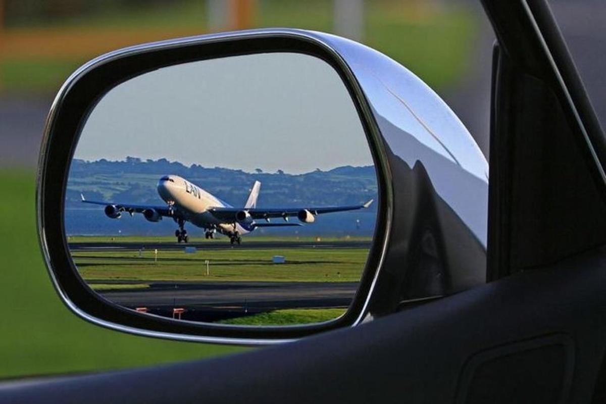 o vedere a unui avion în oglinda retrovizoare laterală a unei mașini