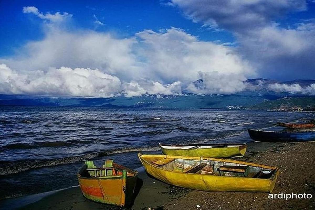 tre barche sedute sulla riva di una spiaggia