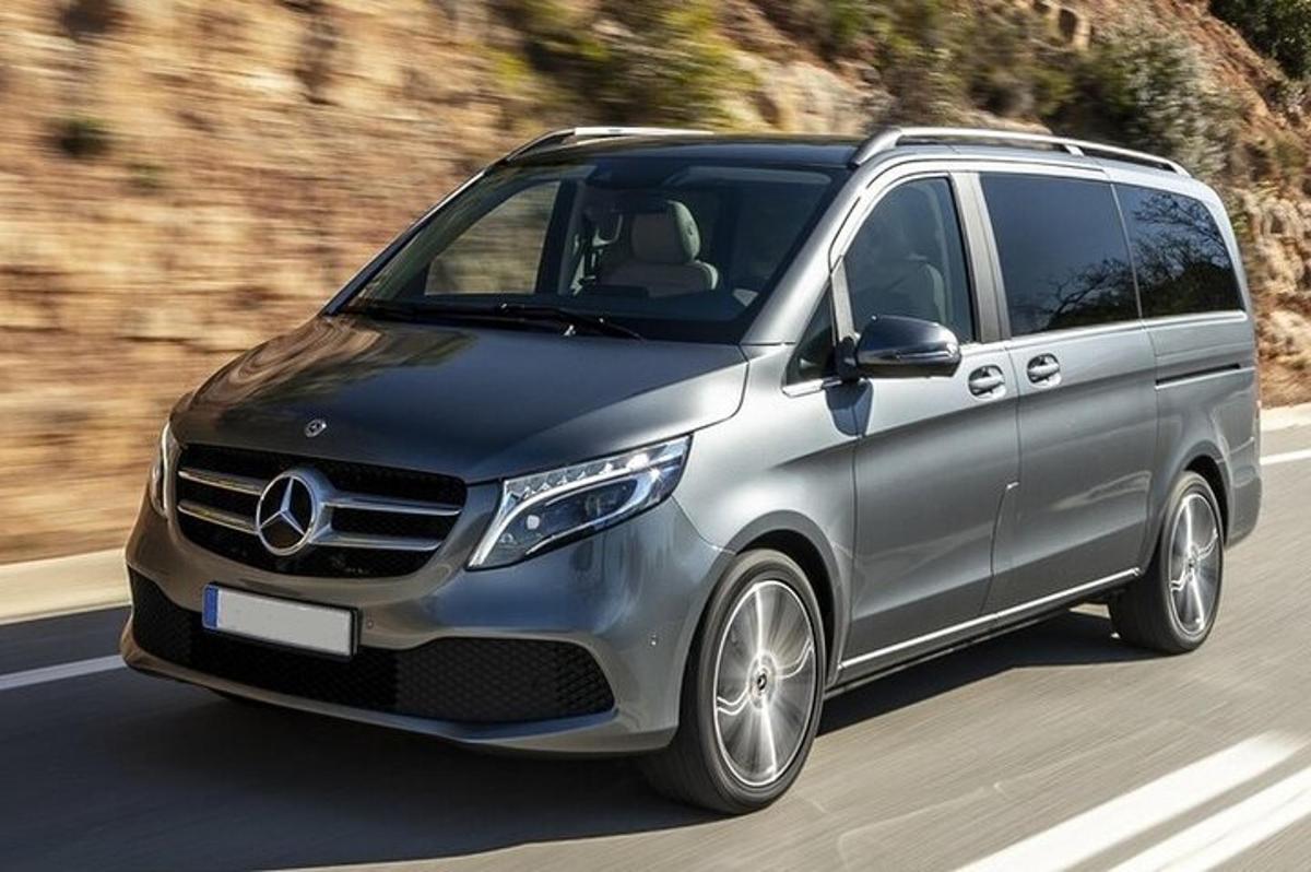 Silfurlitaður Mercedes Benz sendibíll ekur niður götu