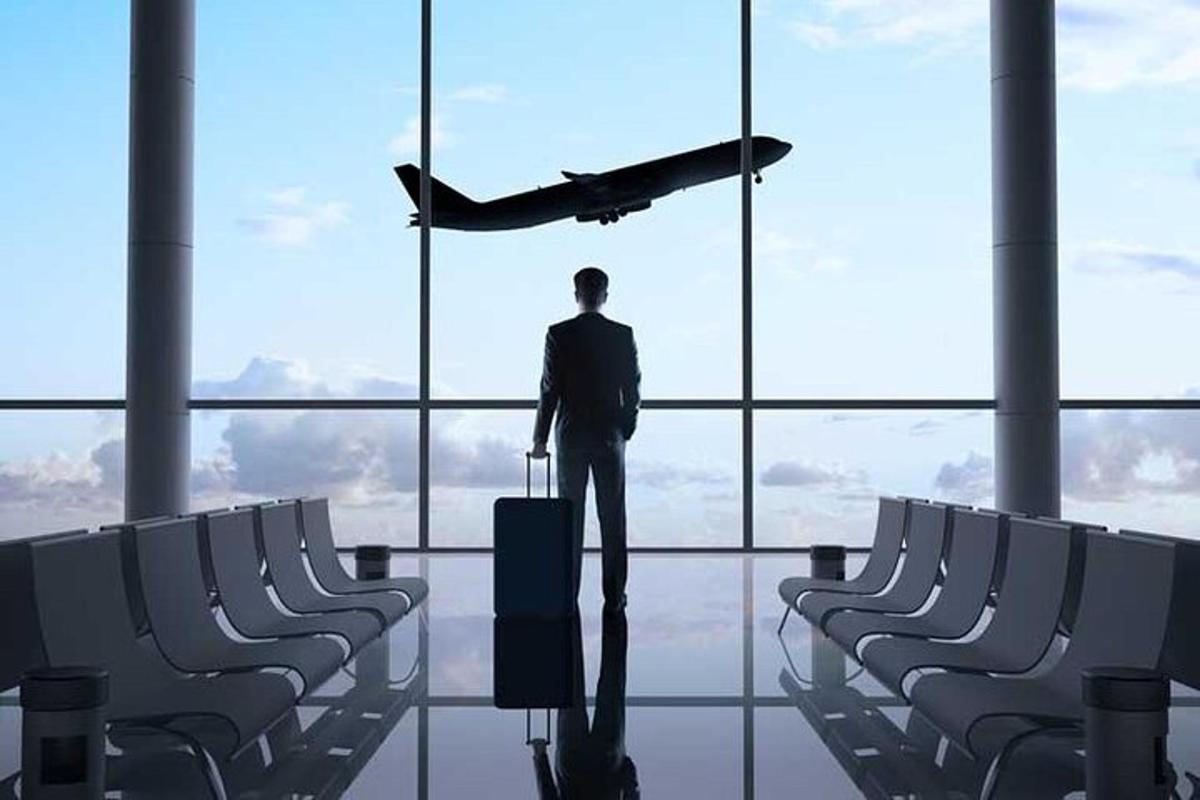 un home dret en un aeroport mirant un avió