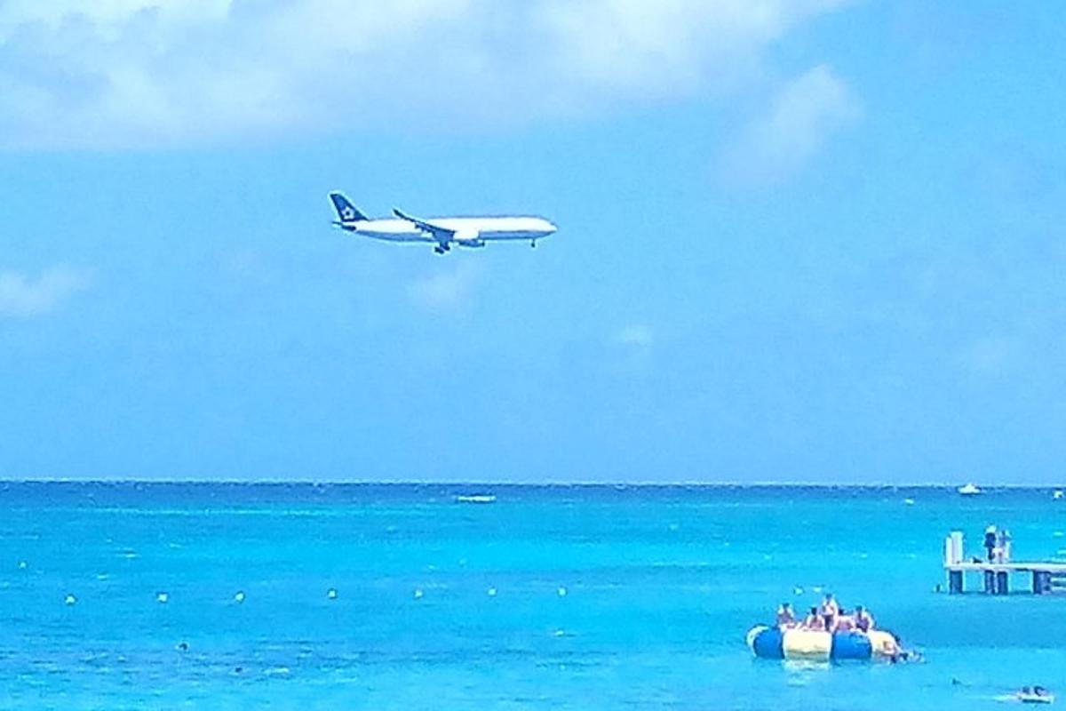 Un avión vuela sobre el océano con gente en un inflable.