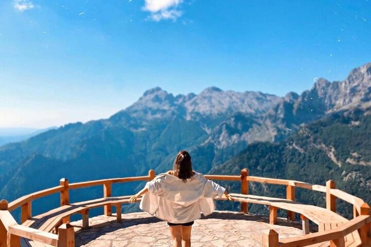 một người phụ nữ ngồi trên băng ghế nhìn về phía những ngọn núi
