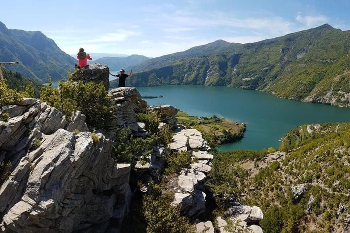 dua orang berdiri di puncak gunung yang menghadap ke danau