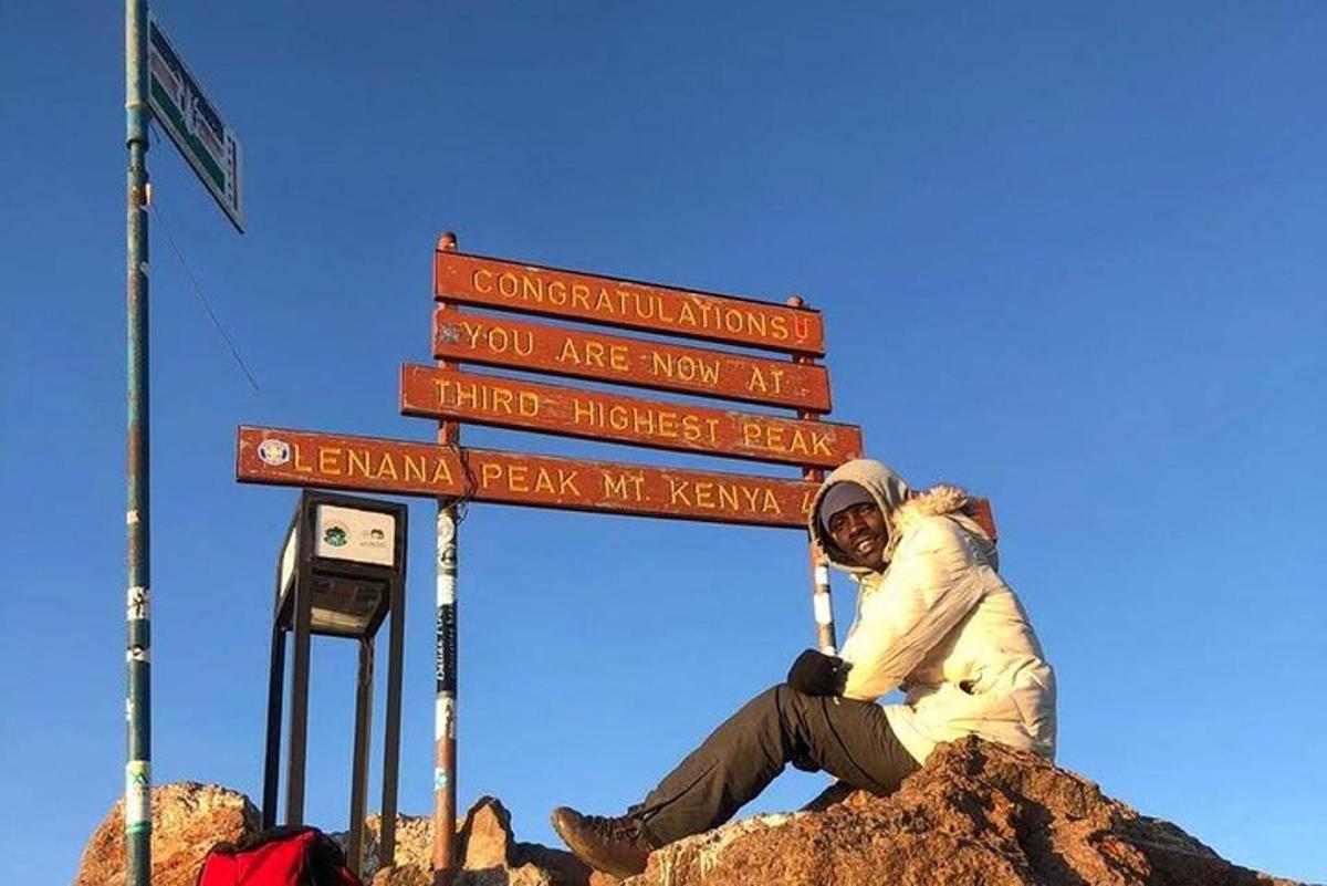 eine Person, die auf einem Schild auf einem Berg sitzt