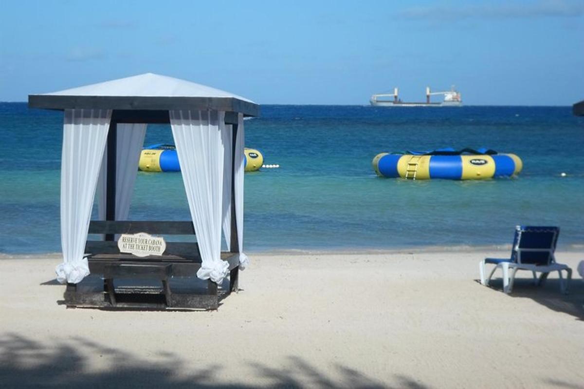 a tent and a chair on a beach with the water