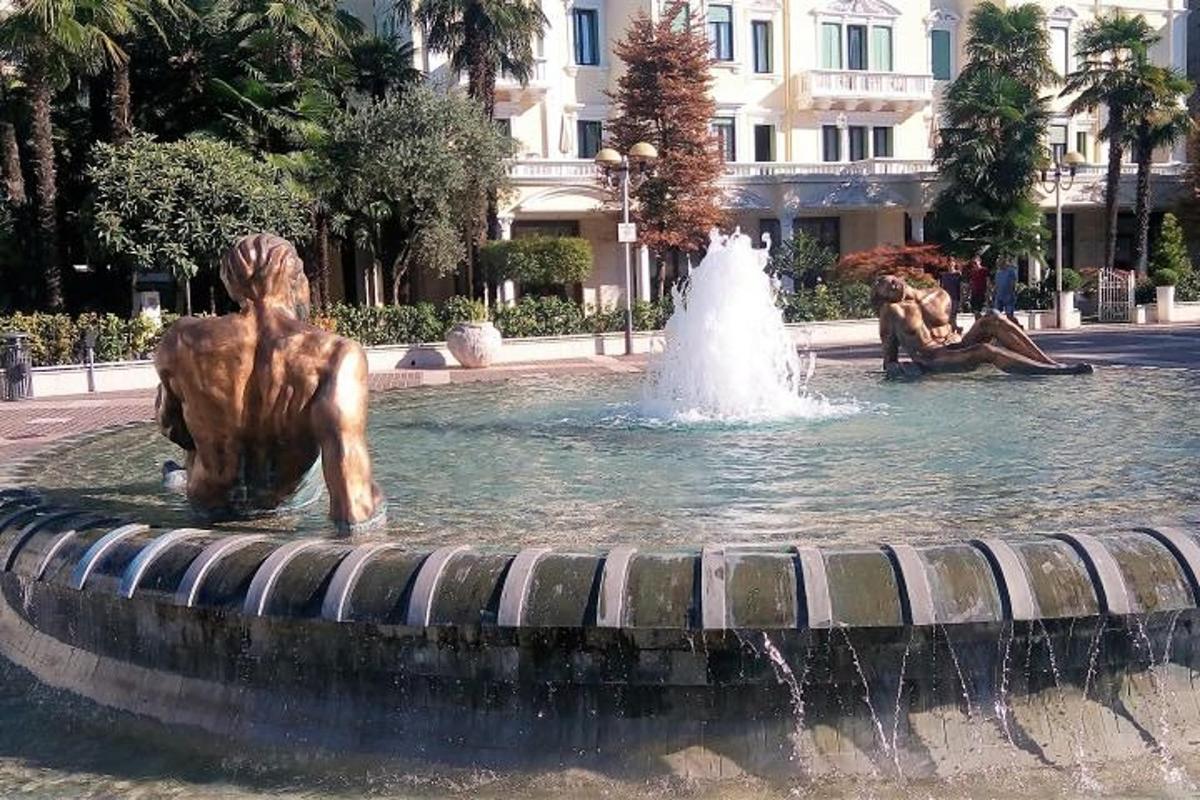 ένα σιντριβάνι με ένα άγαλμα μπροστά από ένα κτίριο
