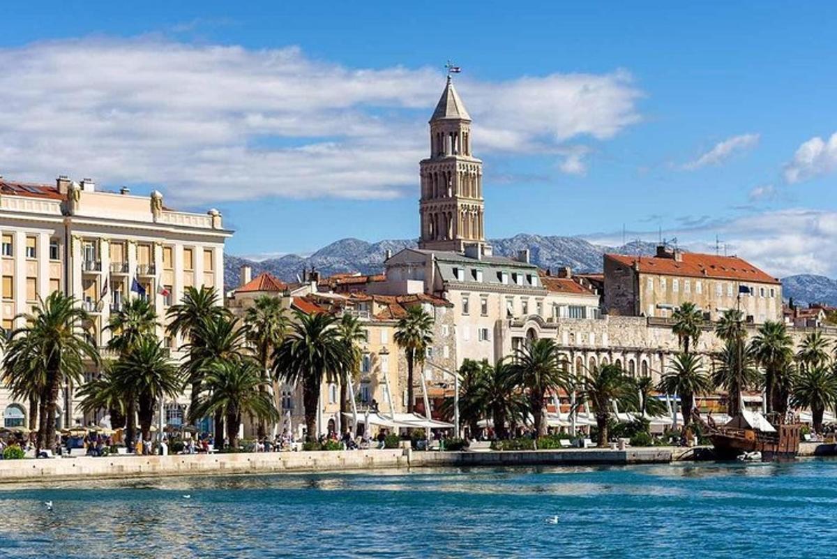 una città con una torre dell'orologio e palme vicino all'acqua