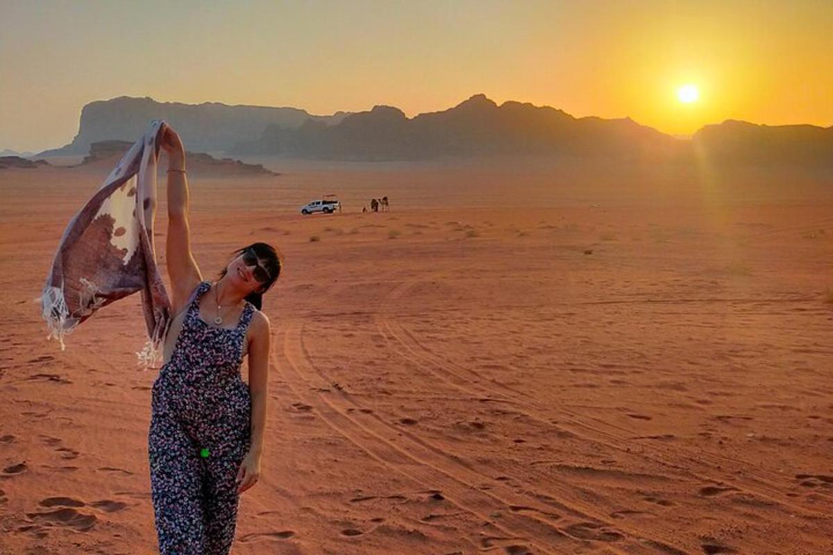 a woman standing in the desert holding a scarf