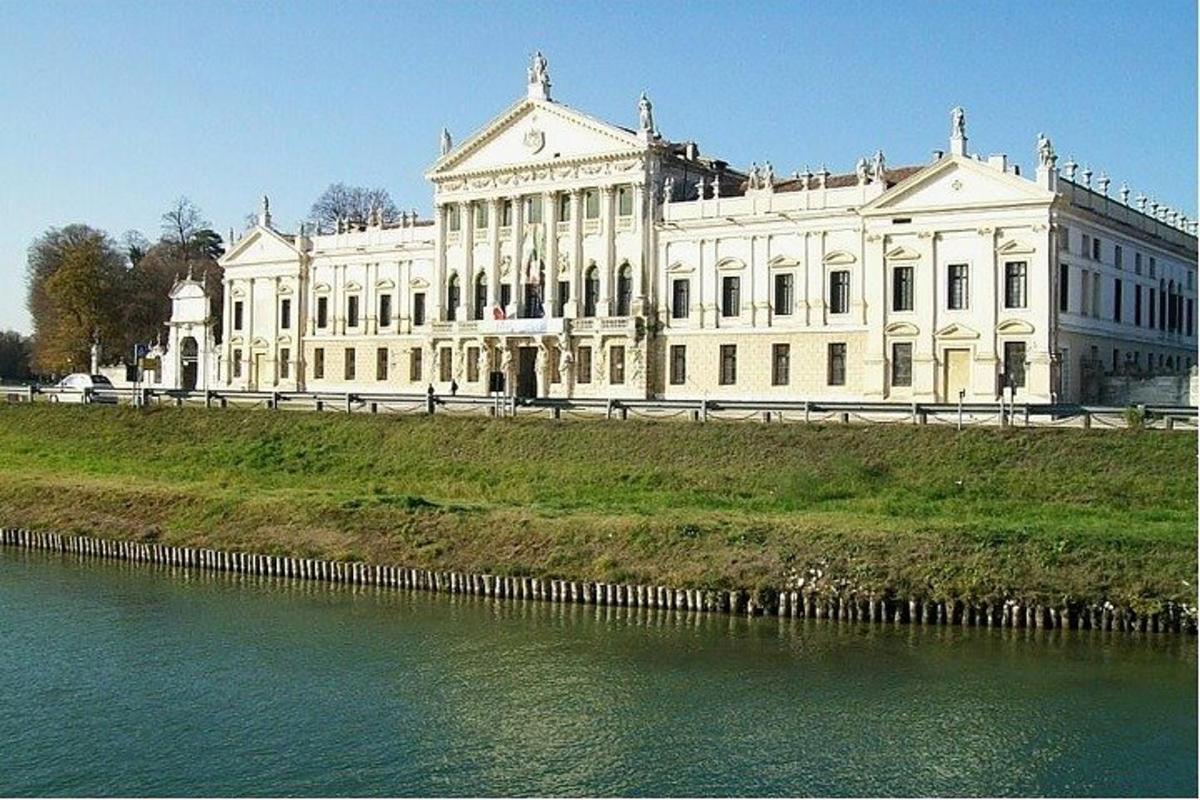a large white building on a hill next to a body of water