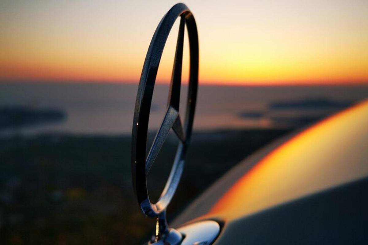 uno specchietto retrovisore laterale di un'auto con il tramonto sullo sfondo