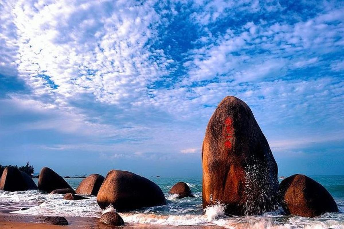a group of large rocks in the water on a beach
