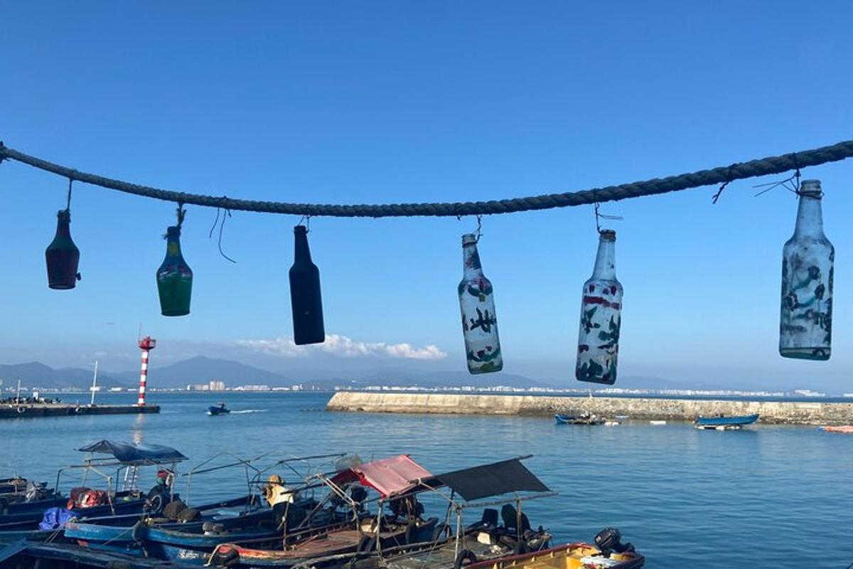 a group of wine bottles hanging from a rope over the water