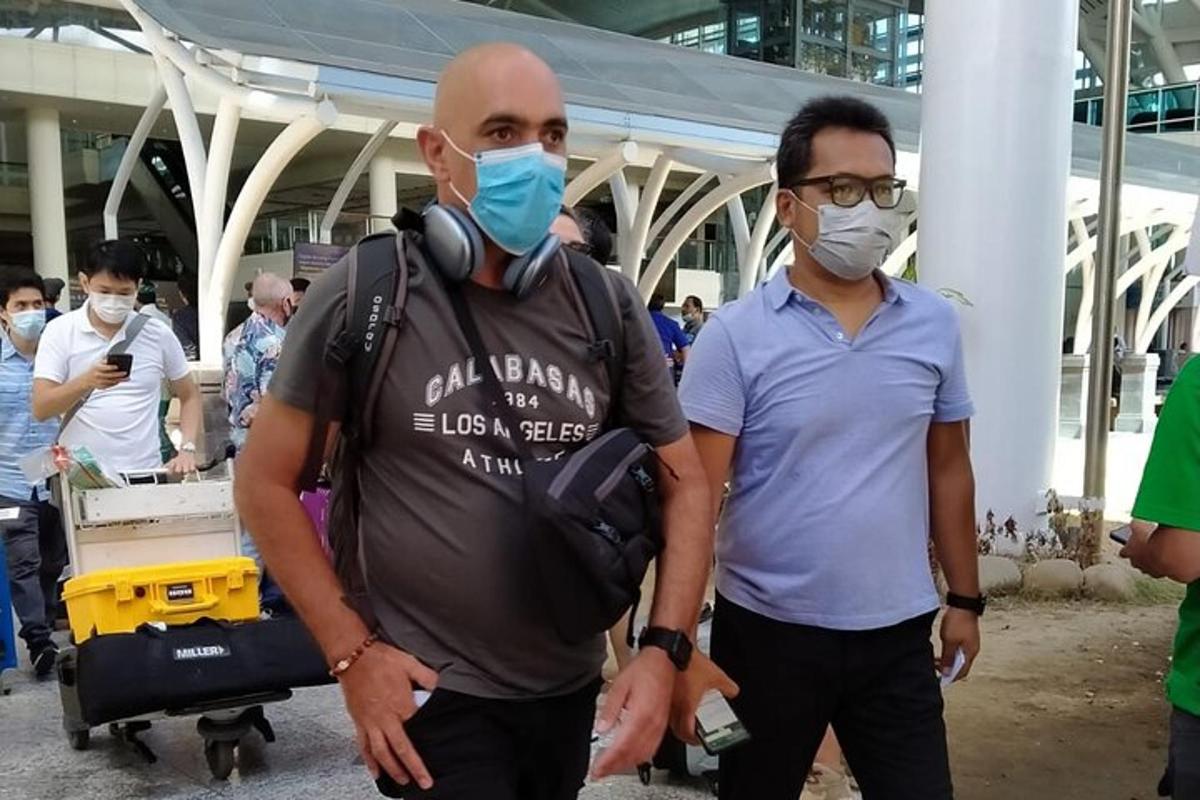 Dos hombres con mascarillas de pie en un aeropuerto
