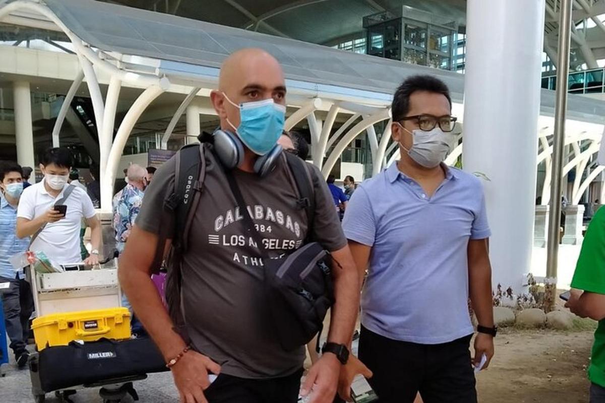 dois homens usando máscaras faciais em pé em um aeroporto