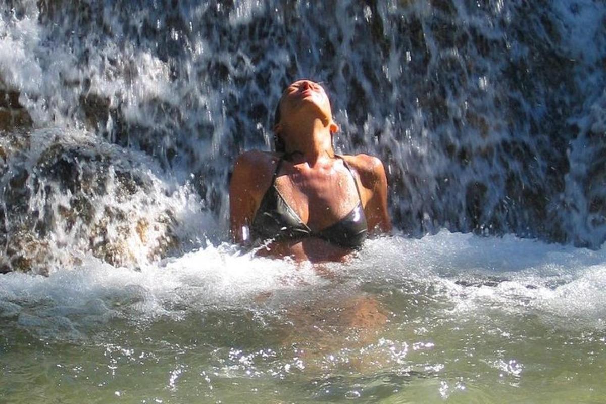 a woman in the water in front of a waterfall
