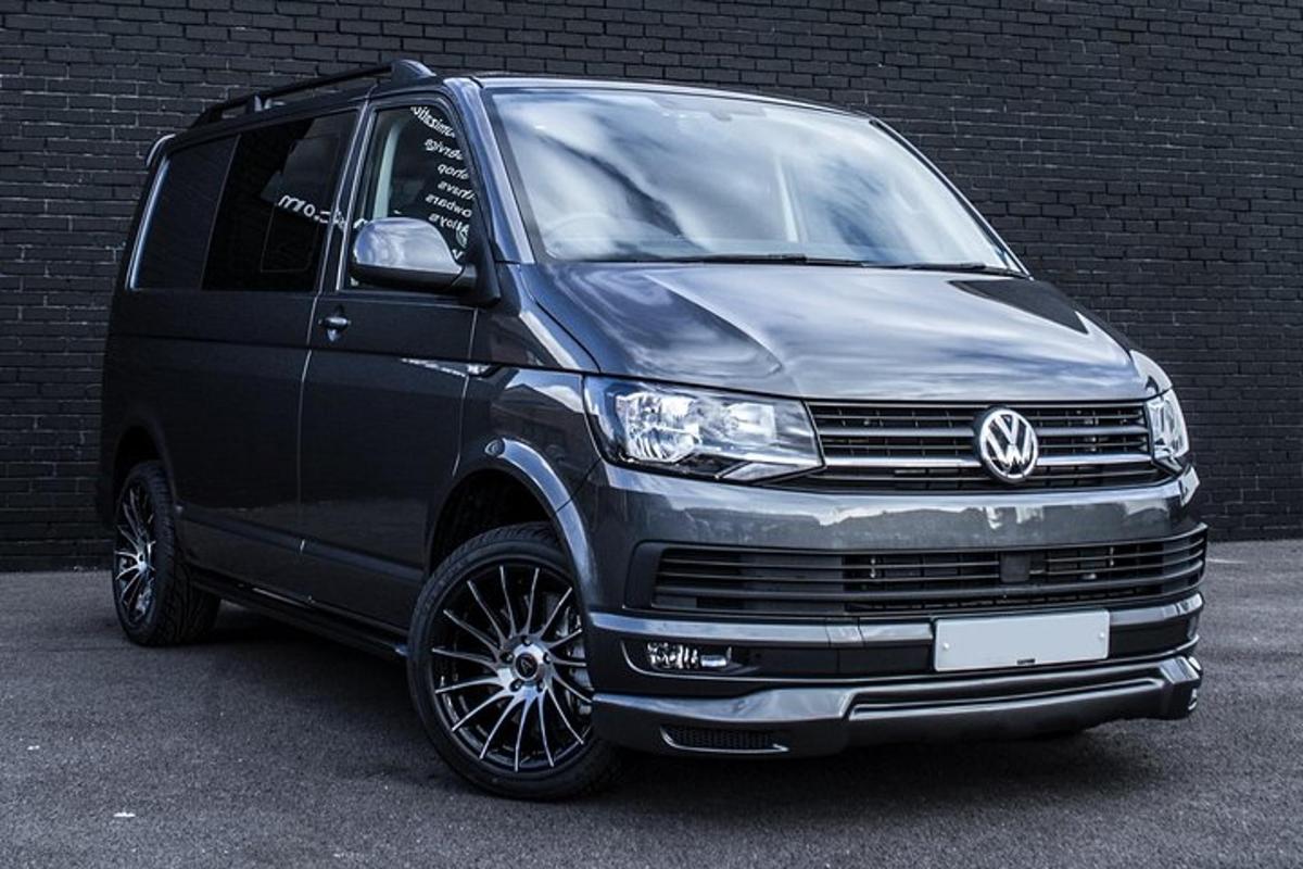 črn kombi parkiran ob opečnati steni