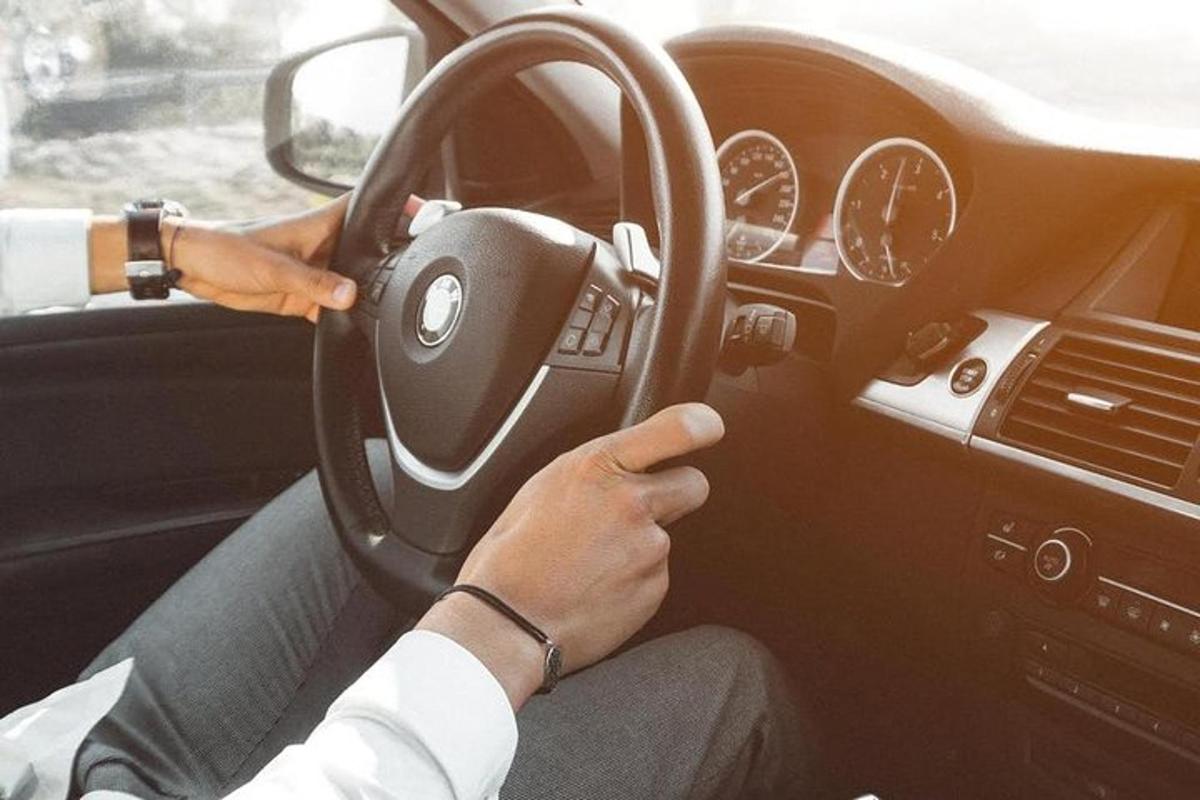 osoba řídící auto a zároveň držící volant