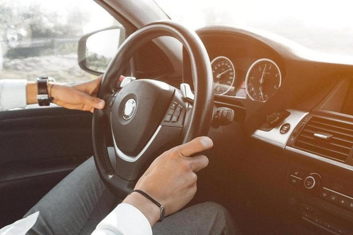 osoba řídící auto s rukama na volantu