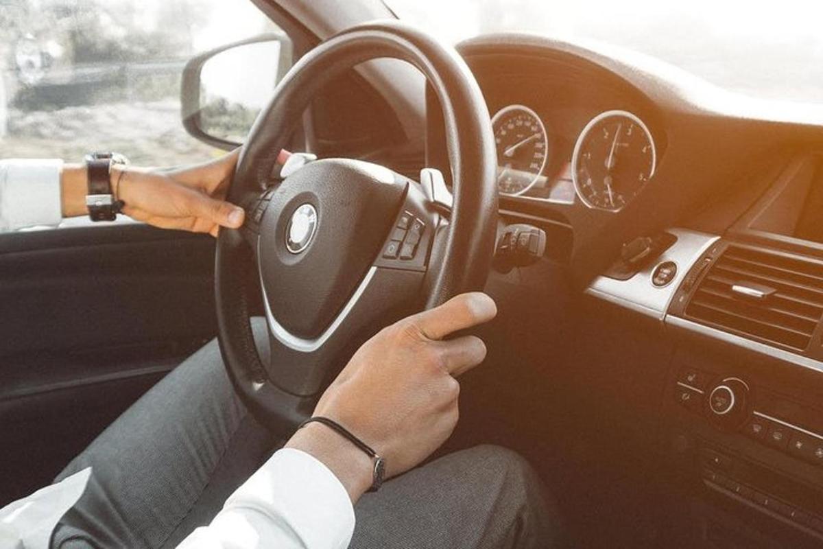 osoba koja vozi automobil dok drži volan