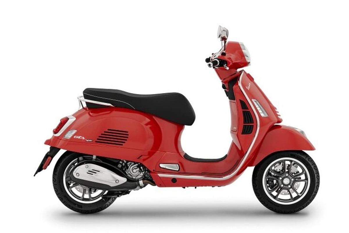 Un scooter rojo estacionado sobre un fondo blanco
