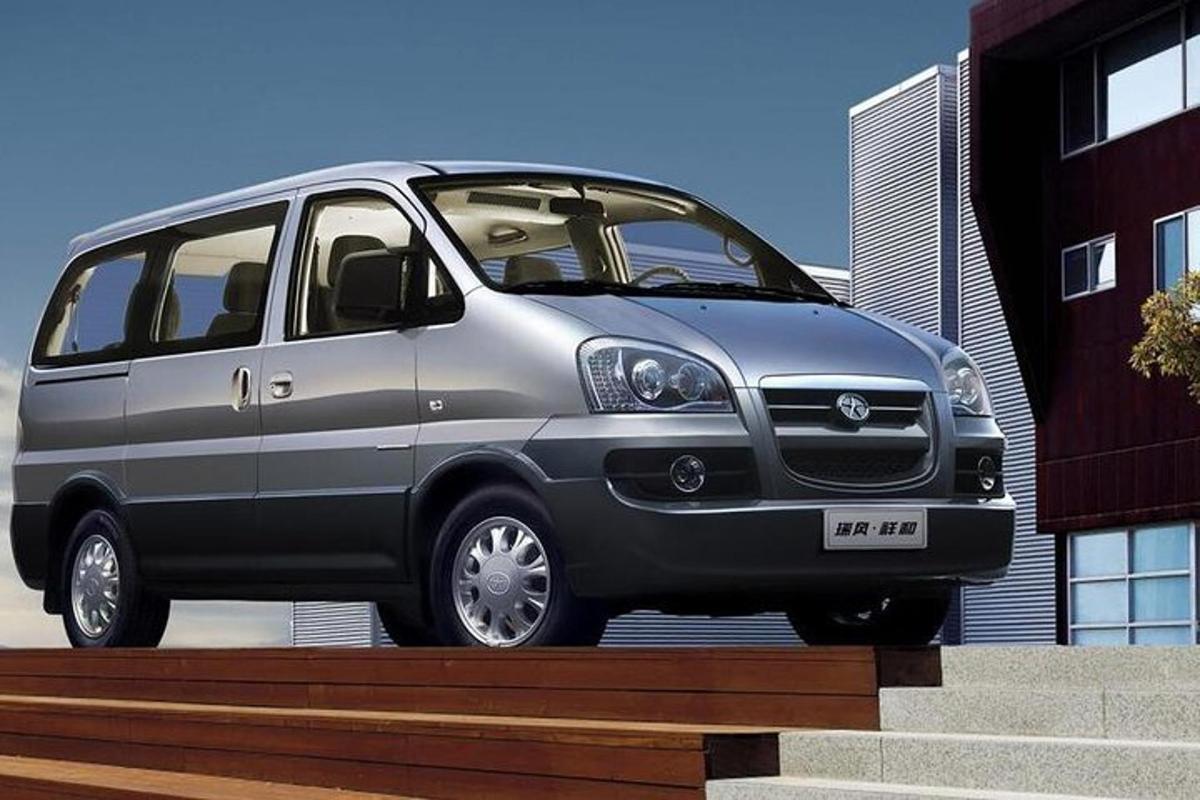 uma van cinza estacionada ao lado de um prédio