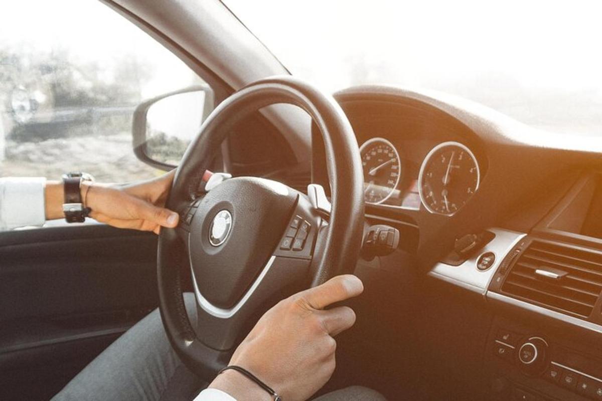 osoba řídící auto s volantem